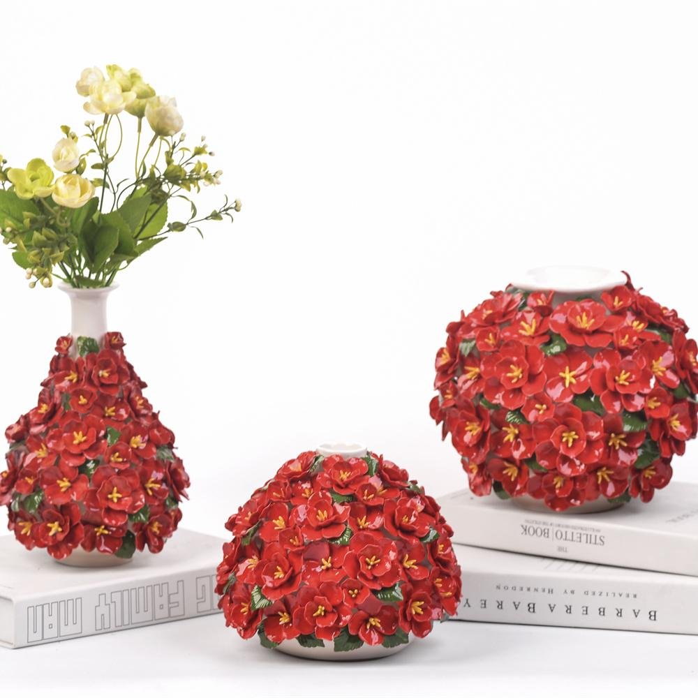 Glazed ceramic vases with sculpted red blossom clusters and green leaf accents (tall + low + round silhouettes).