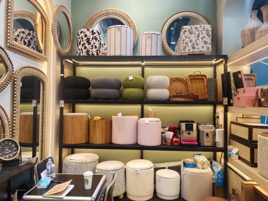 Upholstered ottoman and accent stool samples in cream, gray, olive and blush displayed at the Teruier booth.