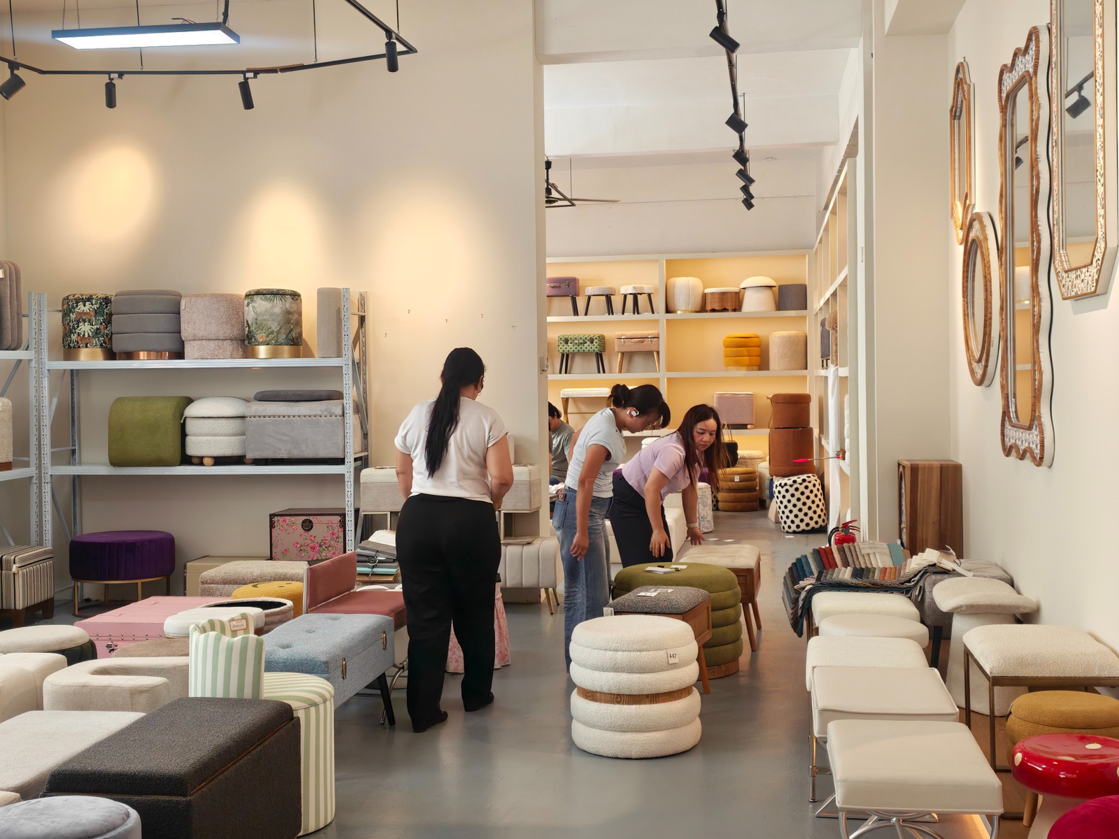 Buyers reviewing upholstered stools, ottomans, and benches in Teruier’s showroom.