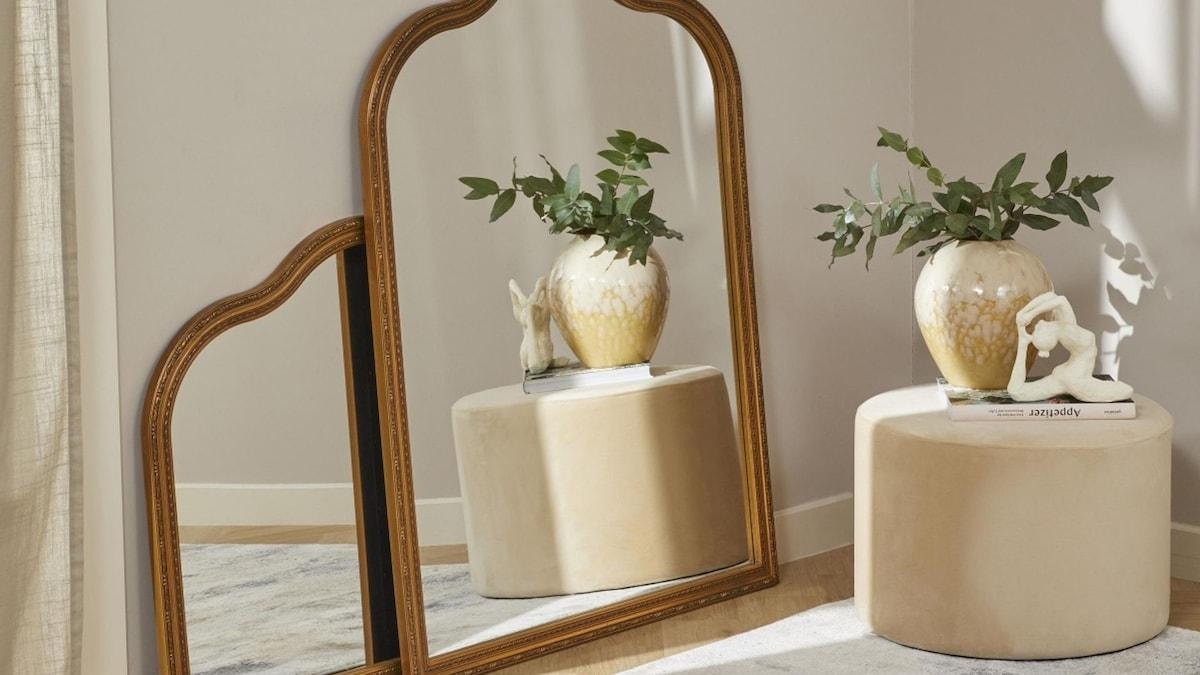 Spring home décor assortment for 2027 featuring a gold wall mirror, upholstered stool and decorative ceramic vase