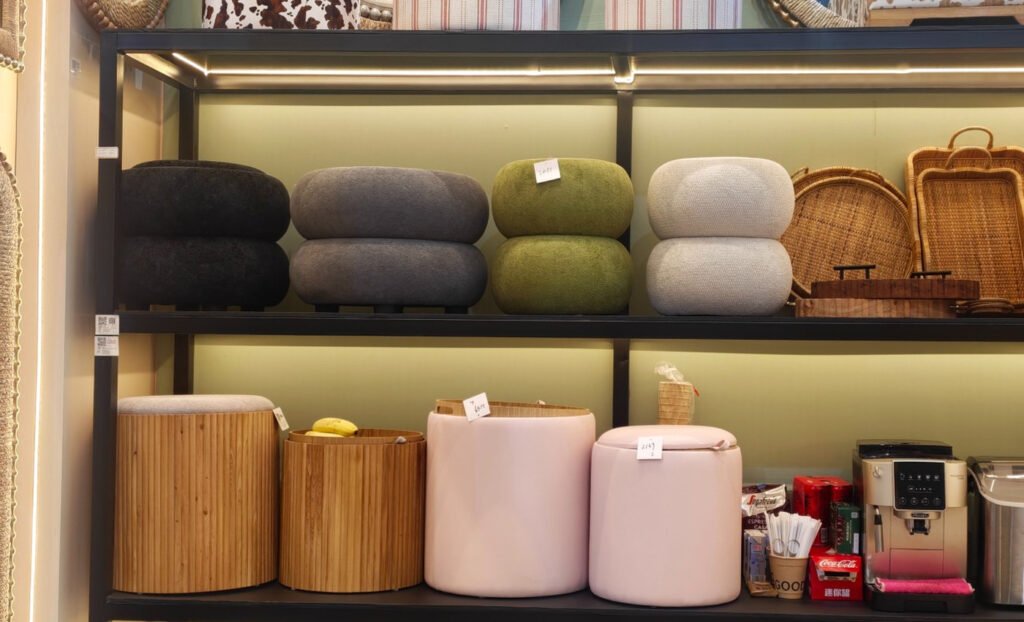 Close view of round upholstered ottomans in charcoal, olive and cream tones shown at Teruier’s Canton Fair display.